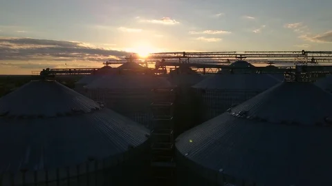 Flight under granaries and elevators or oil storage on sunset Stock Footage 76245204