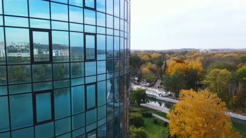 Flight at the window of a skyscraper with reflection and view of the autumn park Stock Footage 163669157