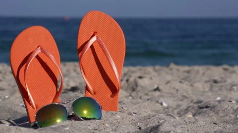 Flip-flops and glasses on the beach Stock Footage 54683469