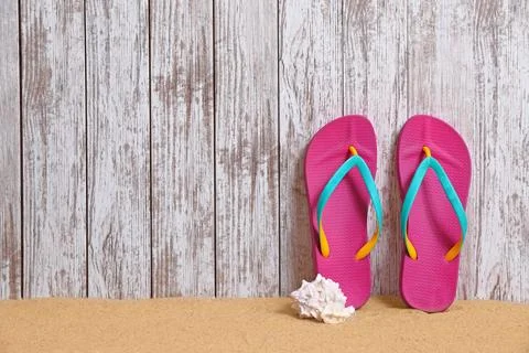 Flip flops and seashell on sand near wooden wall, space for text. Summer beac Stock-Fotos