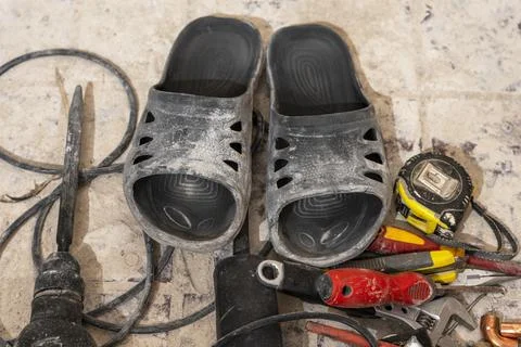 Flip-flops and working tool for apartment renovation Stock Photos