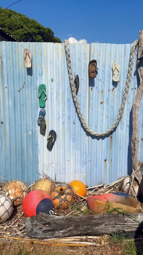 Flip-flops hanging on a blue corrugated fence, Marokopa, New Zealand Stock Footage 333183048