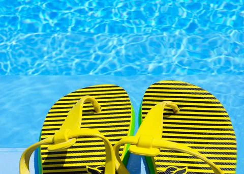 Flip flops in the pool. Bright and colored slippers on the background of the  Stock Photos