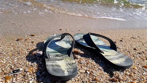 Flip-flops stand on the seashore, Black Flip-flops on the beach Stock Footage 99463633