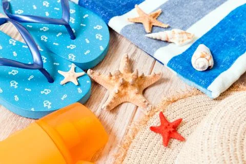 Flip flops, straw hat, starfish, sunscreen bottle, body lotion spray on woode Stock Photos