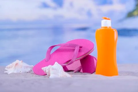 Flip flops surrounded by seashells and sunscreen bottle Stock Photos
