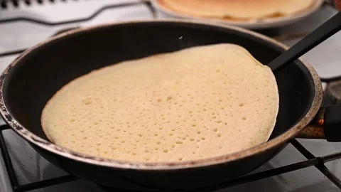 Flip the pancake over in the pan with a spatula. Cooking homemade breakfast Stock Footage 234405663
