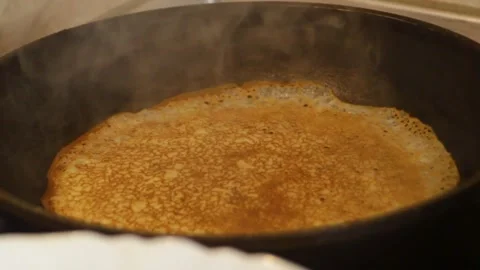 Flip the pancake. Use a spatula to flip the pancake from the baked side to the Stock Footage 304879410