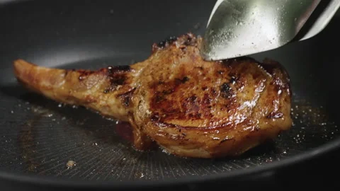 Flip Pork Chops steak is fried in butter in a black iron pan. Stock-Footage 179968082