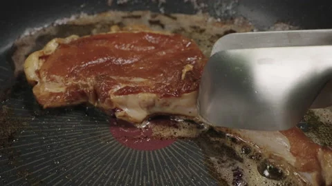 Flip Pork Chops steak is fried in butter in a black iron pan. Stock Footage 179968928