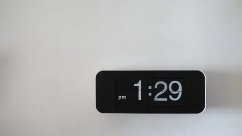 Flip wall clock with black face hanging on a white wall background. Stock Footage 317499826