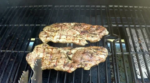 Flipping pork steaks on the grill Stock Footage 37668245