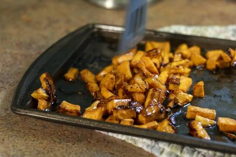 Flipping Roasted Sweet Potato Cubes with Spatula on Baking Pan 写真素材