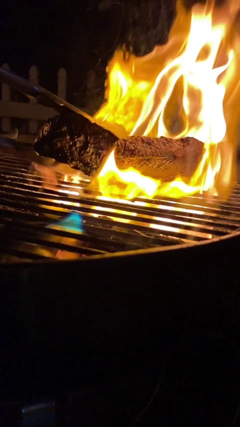 Flipping a stak on a bbq grill with flames Stock Footage 230053165