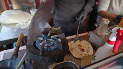 Flipping a thick layered paratha on a large flat tawa, indian street food Stock Footage 326124465