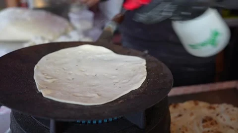 Flipping a thick layered paratha on a large flat tawa, indian street food Video stock 326124526