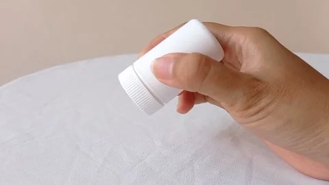 Flipping up a tiny white jar on a white table Stock Footage 145562685