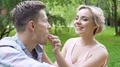 Flirty blonde feeding handsome young man with sweet raspberry, tender picnic HD Footage