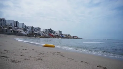 A float in the form of a yellow banana on the shore being moved by the waves of 库存影片 195126030