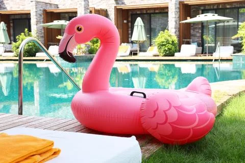 Float in shape of flamingo on wooden deck near swimming pool and sunbeds at.. 写真素材