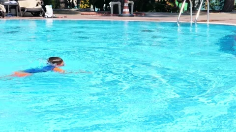 Floating boy on blue swimming pool in resort. Summer vacation, tourism concept Stock Footage 169950546