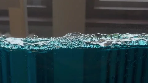 Floating bubbles move across vivid blue water, creating a clean abstract Stock Footage 345858256