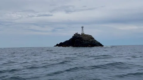 Floating close to a little island with a lighthouse Stock Footage 220693559