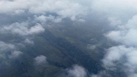 Floating clouds drift above a misty, green mountain range Vidéo 345502635