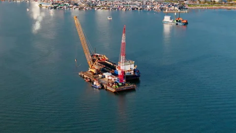 Floating crane barge beside dredging ship during coastal water maintenance work Stock Footage 338999820