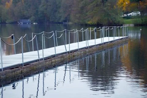 A floating dock, also known as a pontoon pier, against a backdrop of an aut.. Stock Photos