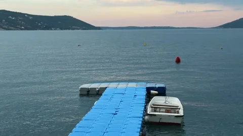 Floating dock and small boat rest on calm Kotor Bay water in Montenegro at Stock Footage 344902535