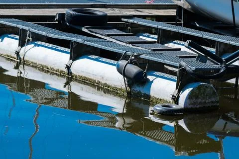 Floating dock with reflections in calm water at the marina Stock Photos