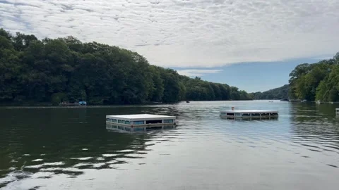 Floating Docks Resting on Calm Lake Surface with Forest Shoreline Stock Footage 344057730