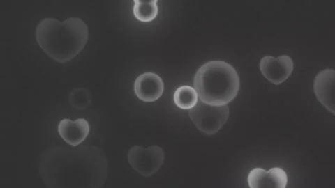 Floating glowing heart shapes and circles rising against dark textured backdrop Stock Footage 345217552