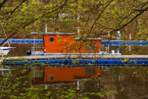Floating house with round window docked at marina - reflection in water through Stock Photos