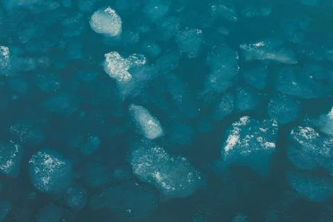 Floating ice chunks are seen on water, creating a mixture of shapes in a cold Stock Photos