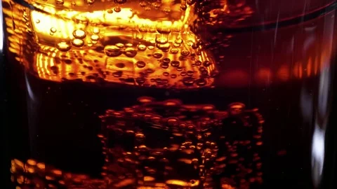Floating ice cube in a glass of Cola - Soda drink in slow motion Stock Footage