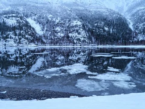 Floating ice flakes on water with mountain reflection on surface Stock Photos