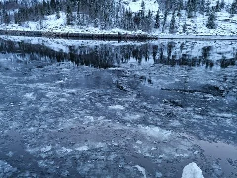 Floating ice flakes on water with mountain reflection on surface Stock Photos