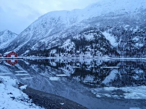 Floating ice flakes on water with mountain reflection on surface Stock Photos