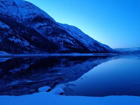 Floating ice flakes on water with mountain reflection on surface Stock Photos
