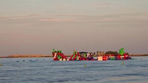 Floating inflatable water park playground in the sea during golden hour suns Stock Footage 345807780