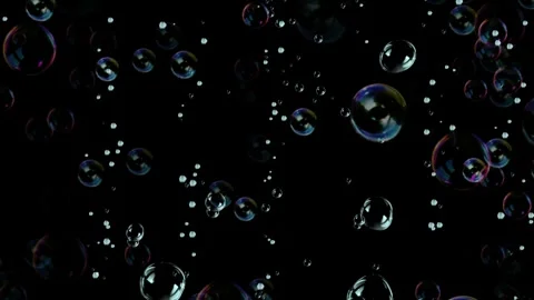 Floating iridescent soap bubbles drifting slowly across dark background with Stock Footage 340613145