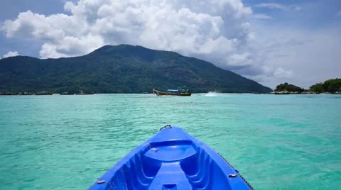 Floating in a kayak on  turquoise waters while a tail boat passes by Stock Footage 67435839