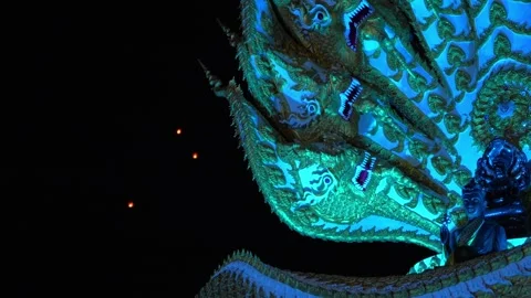 Floating Lanterns Rise Behind Naga Statue at Yi Peng Festival Stock Footage 324452860