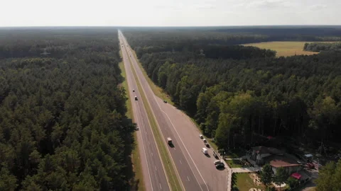 Floating over a long stretch of highway in the middle of a lush green forest.  库存影片 169483128