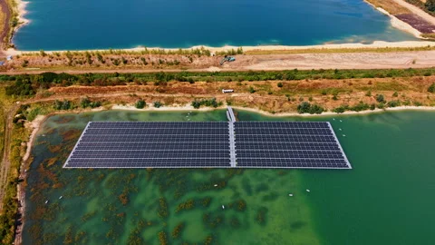Floating photovoltaic array between two quarry ponds. Dark panel rows cover part Stock Footage 346483071