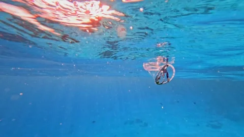Floating plastic cup in calm sea surface representing threat of waste to marine Stock Footage 340598753
