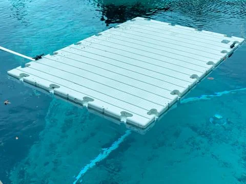 Floating platform on clear blue water seen in a residential area during midda Фото