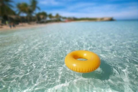Floating ring on blue clear sea with beach, shallow dof Stock Photos